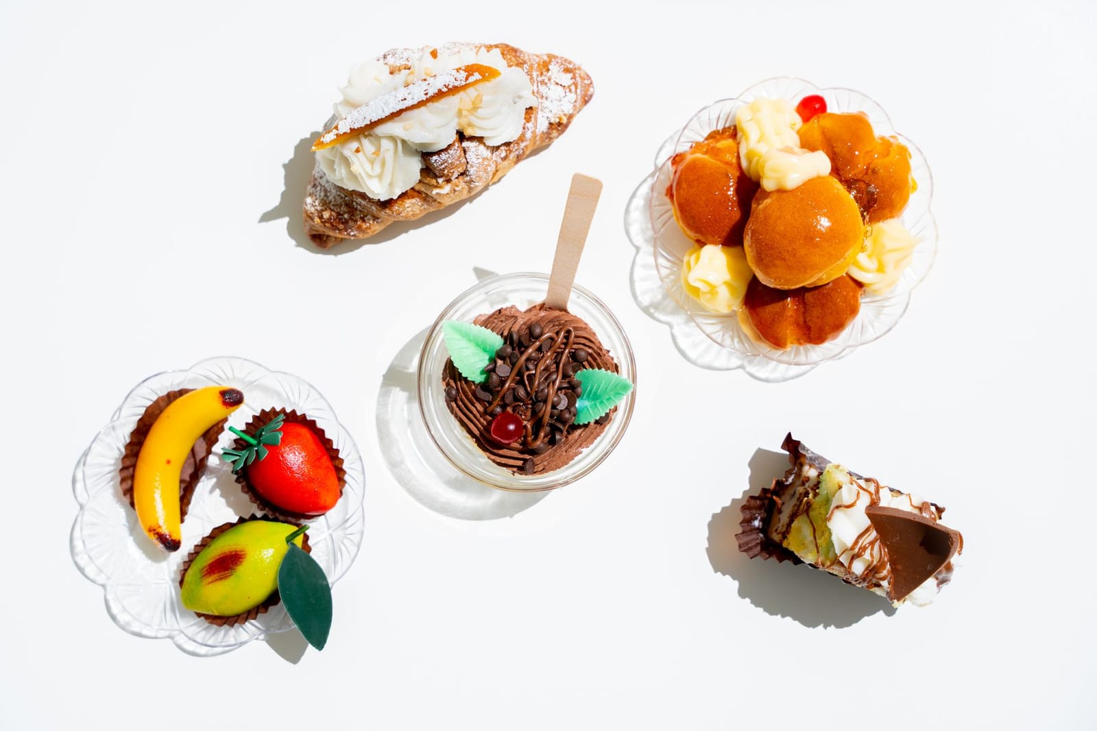 Assorted fruit shaped almond paste sweets and bakery pastries on a white background.