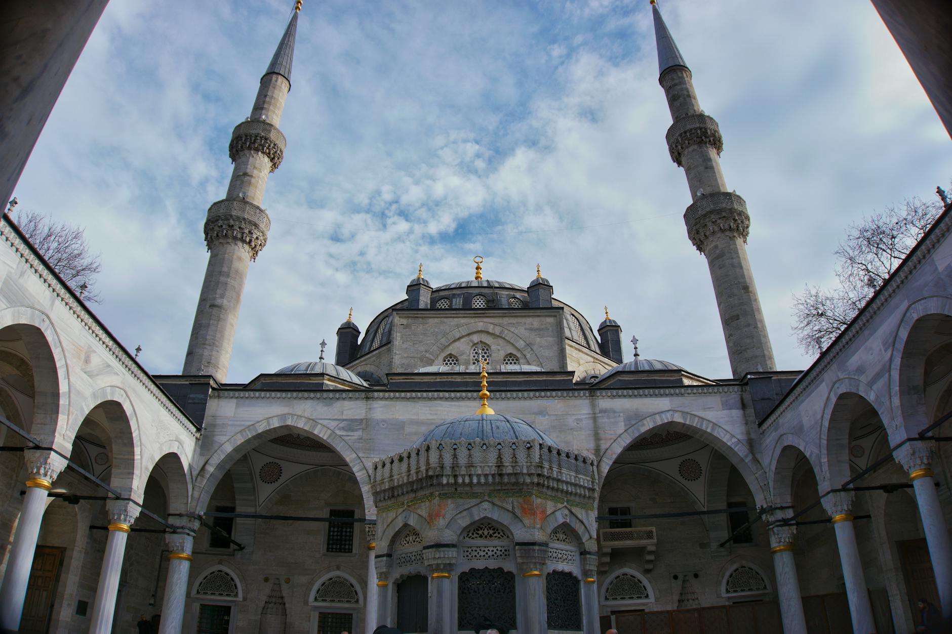 The sunlit courtyard and fountain of the historic Atik Valide Mosque complex.