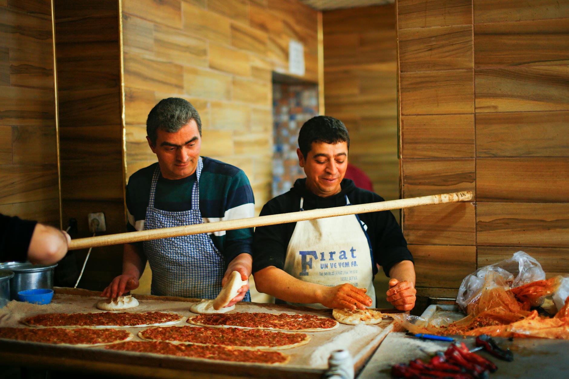 Local bakers in a Turkish kitchen preparing thin dough for traditional meat topped lahmacun.
