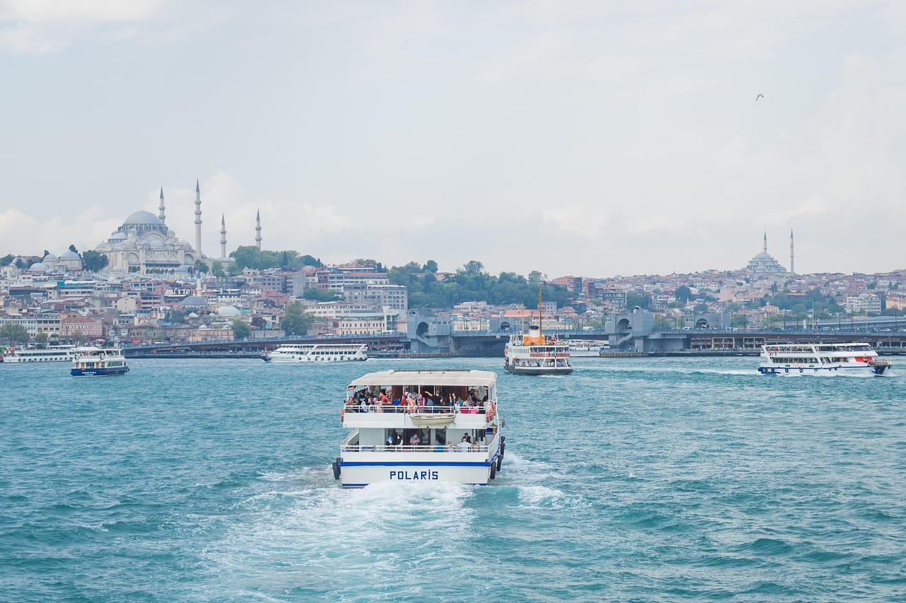 A passenger ferry navigates the Bosphorus waters against the historic Istanbul cityscape.