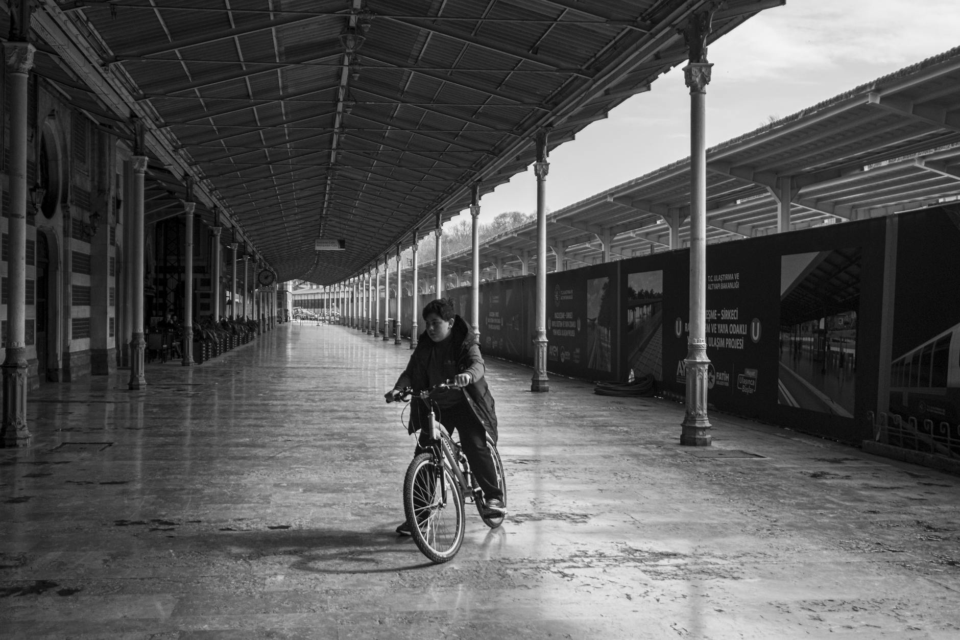 A person rides a bicycle through the wide historic platforms of Sirkeci Station in Istanbul.