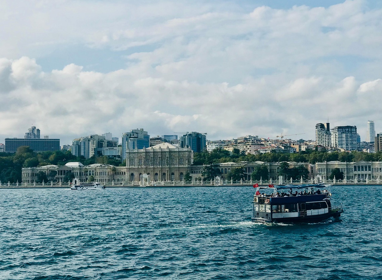 View of Dolmabahçe Palace from the Bosphorus with a tourist boat passing by.