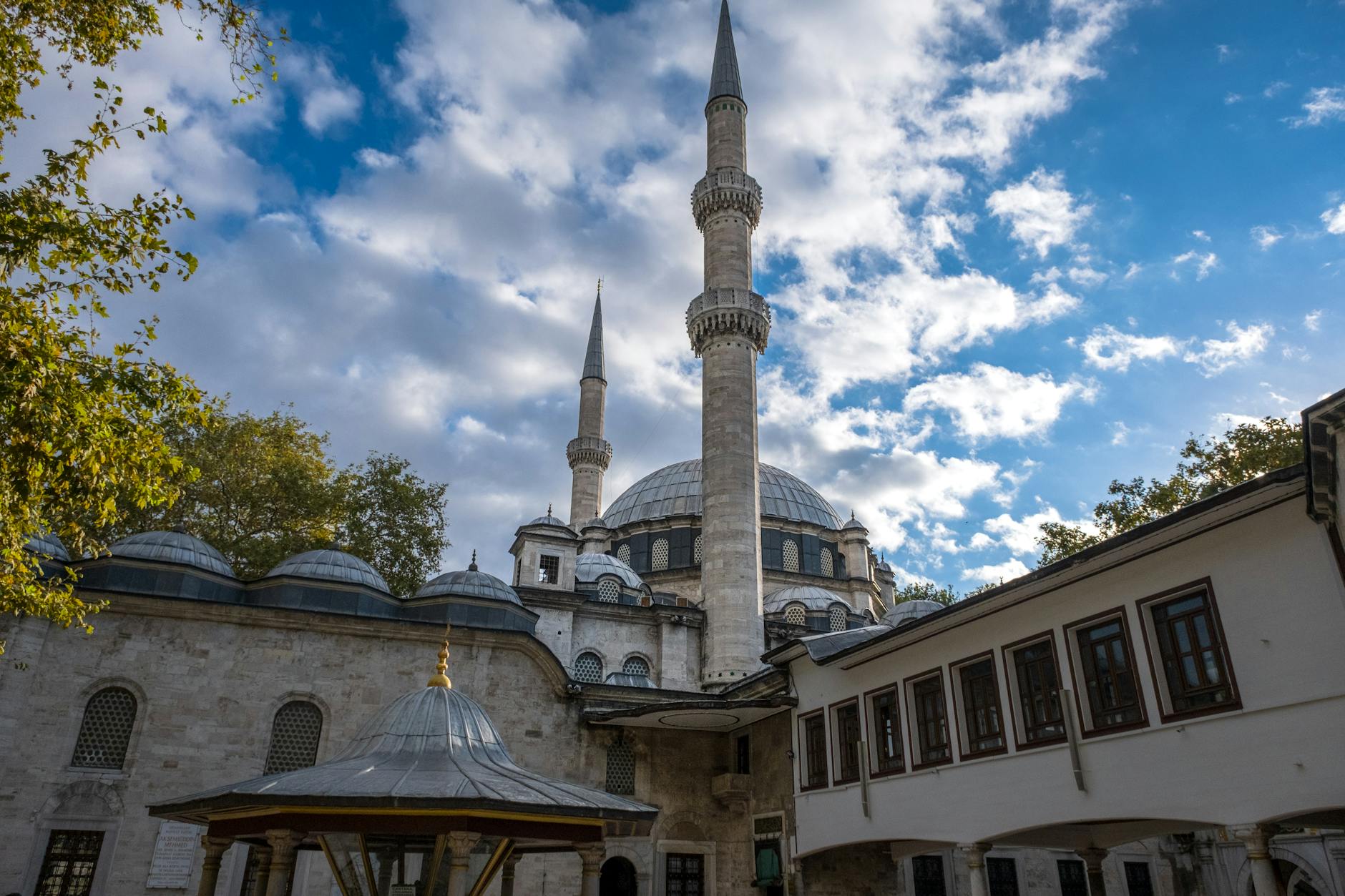 The historic Eyüp Sultan Mosque stands against a blue sky with soft white clouds.