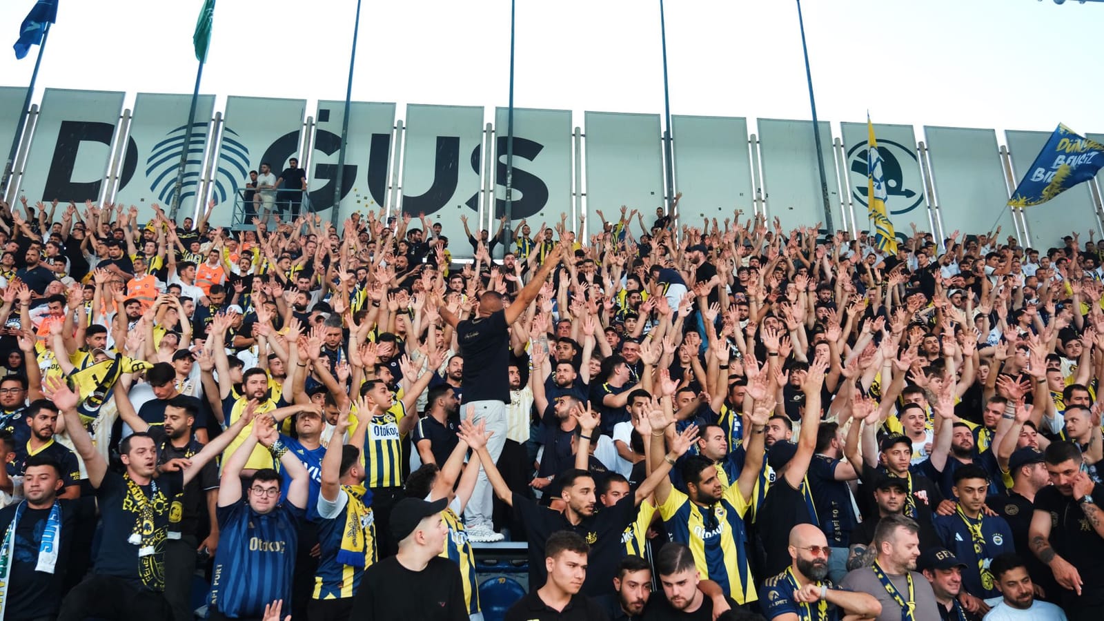 Fenerbahce supporters chant and wave banners in the stadium stands.