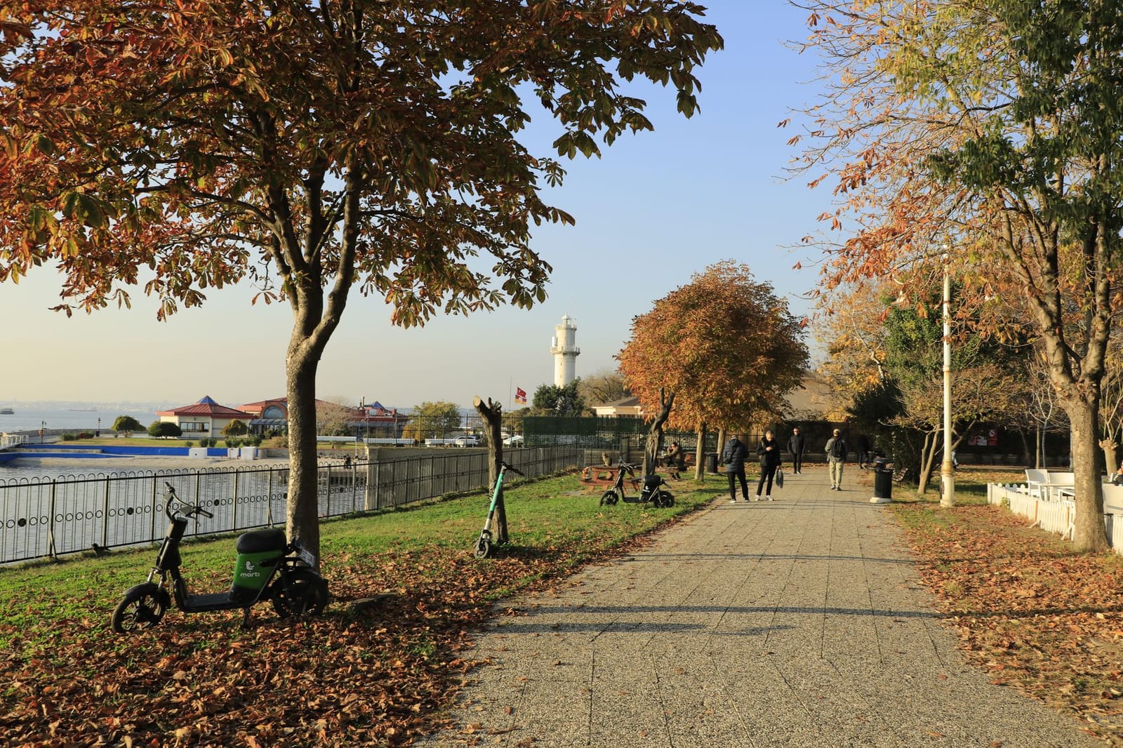 Paved walking path through Fenerbahçe Park with historic lighthouse in the background.
