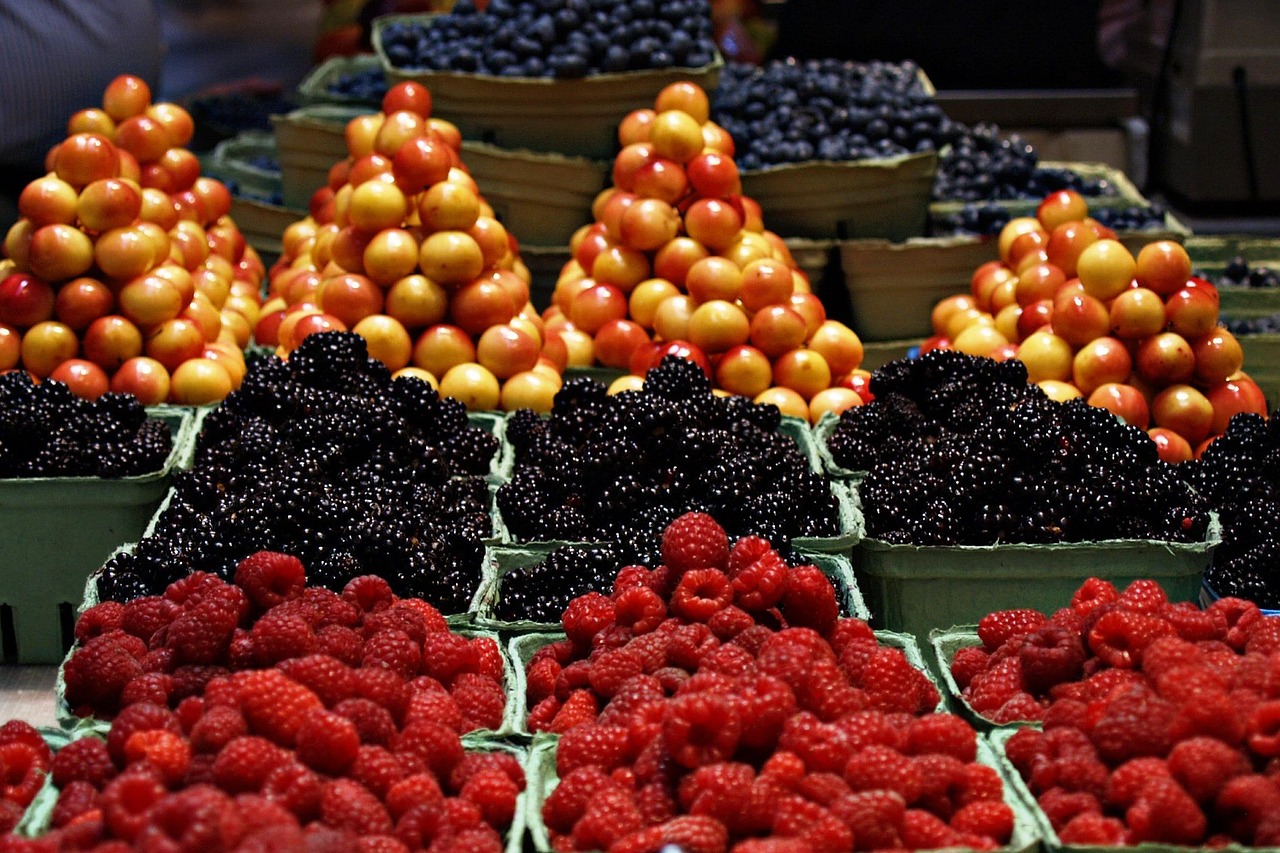 Boxes of raspberries, blackberries, and cherries displayed at a local produce market.