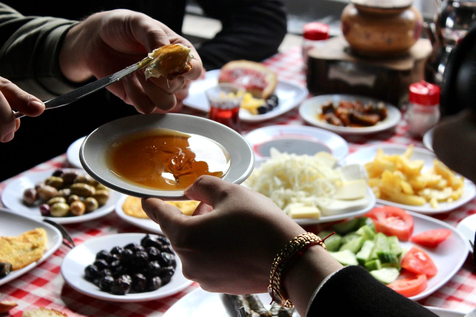 Dipping fresh bread with kaymak into golden honey during a traditional Turkish breakfast.