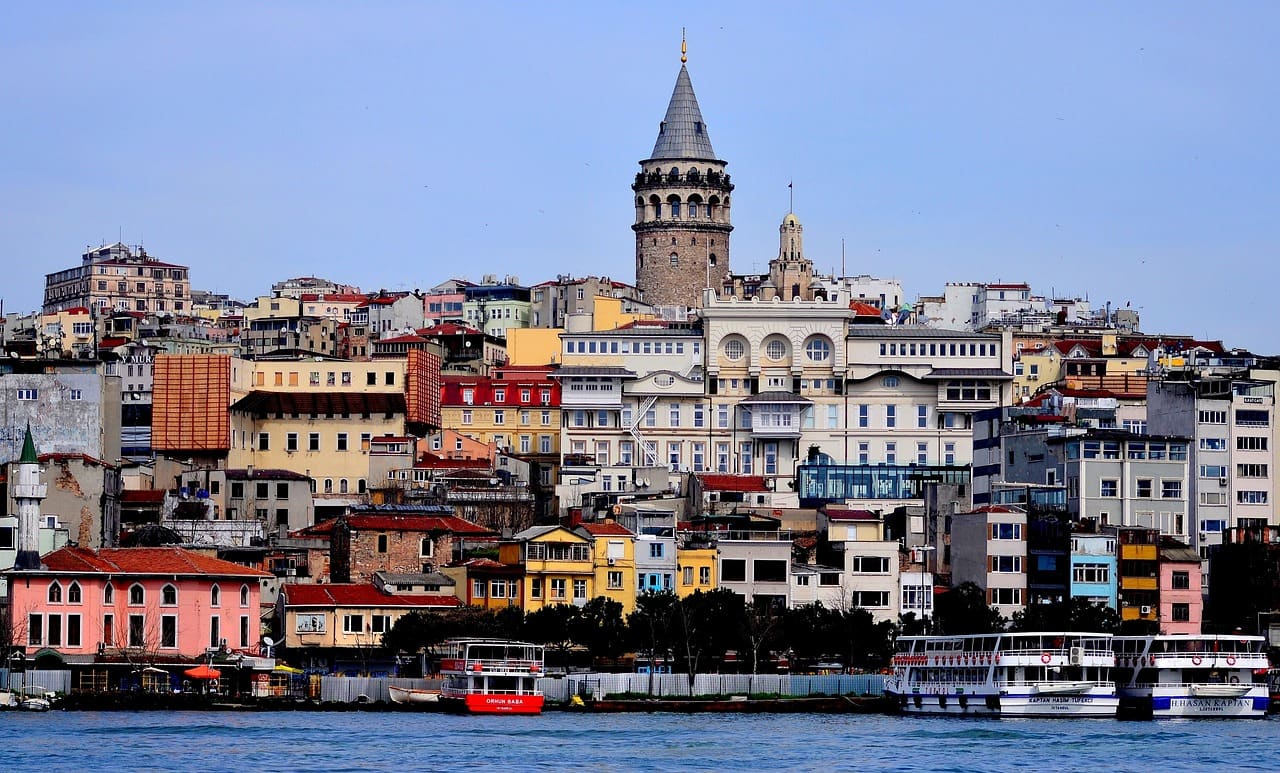 Galata Tower towering over the colorful hillside district of Istanbul under a blue sky.