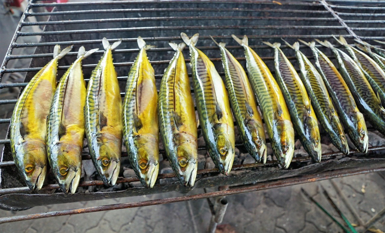 Fresh mackerel fish grilling on a charcoal rack at a neighborhood seafood restaurant.