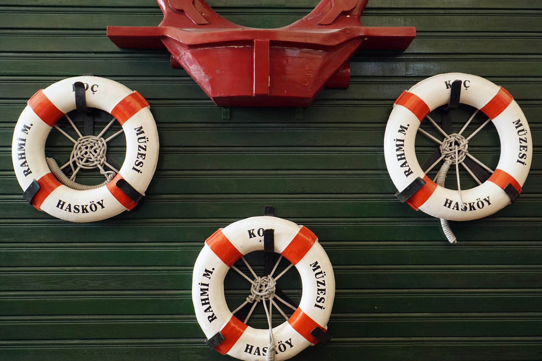 Three lifebuoys marked with Hasköy and museum name hang on a green wooden wall.