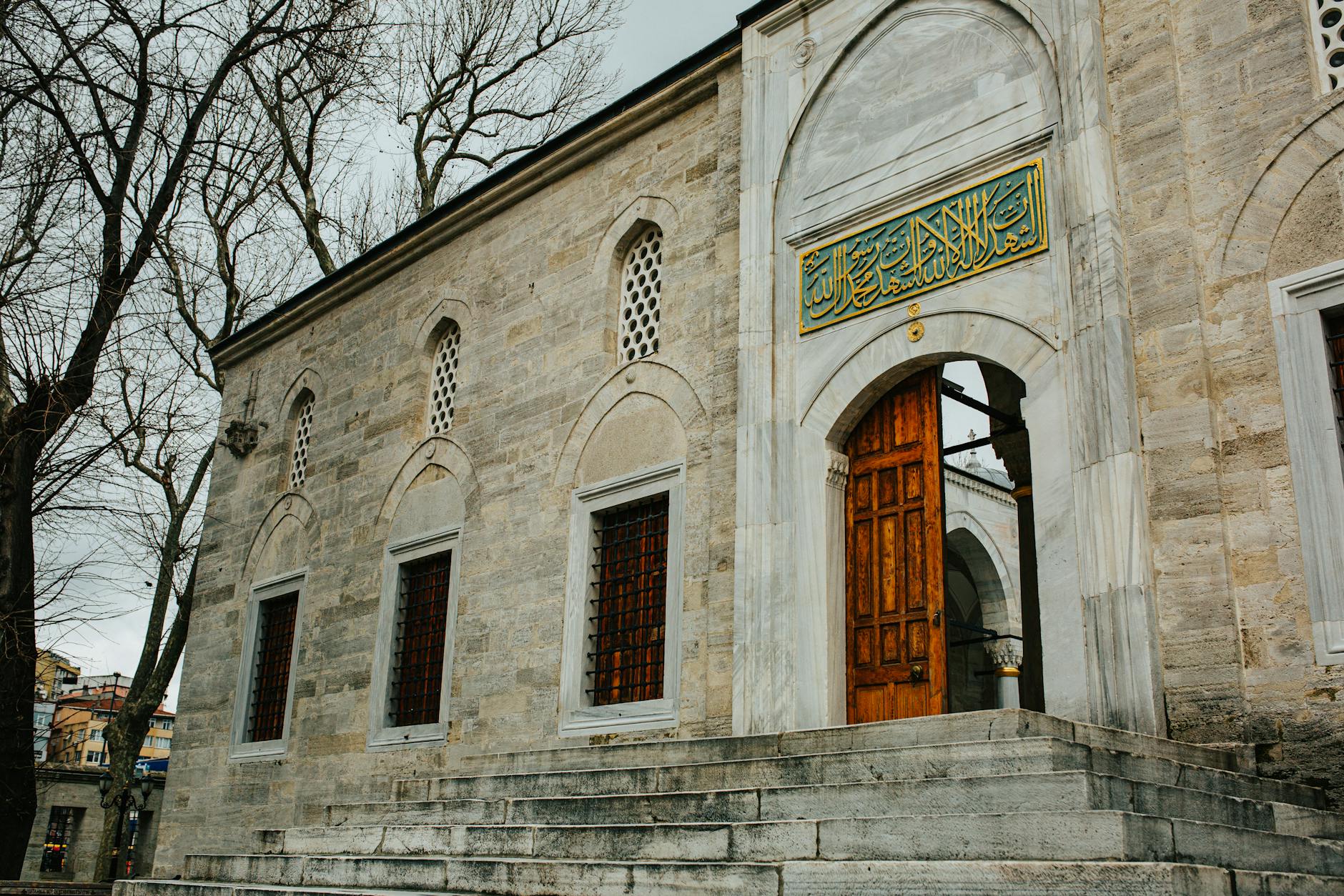 A historic stone entrance with an ornate wooden door and calligraphy.