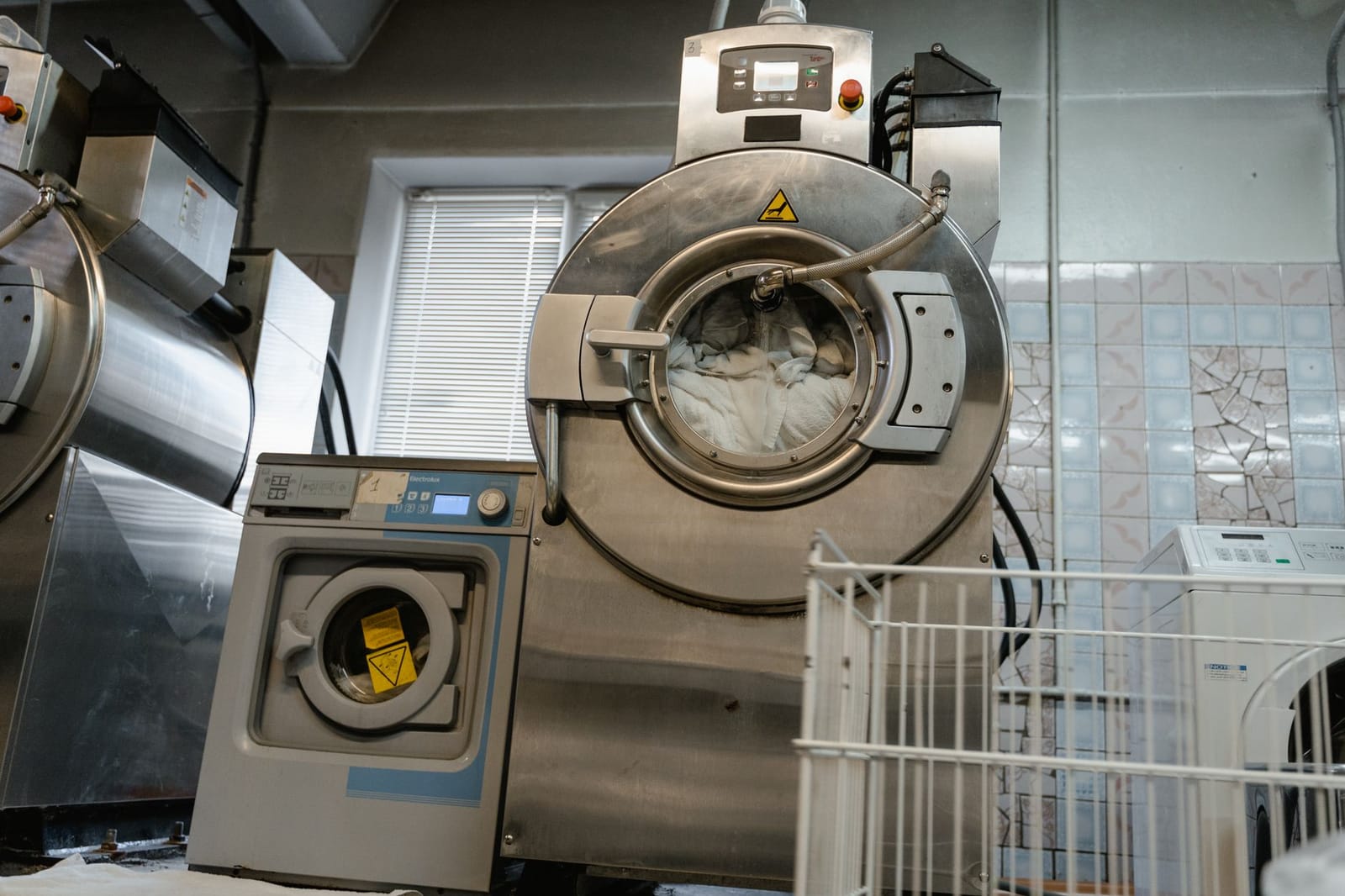Large industrial laundry machine loaded with white linens in a washing facility.