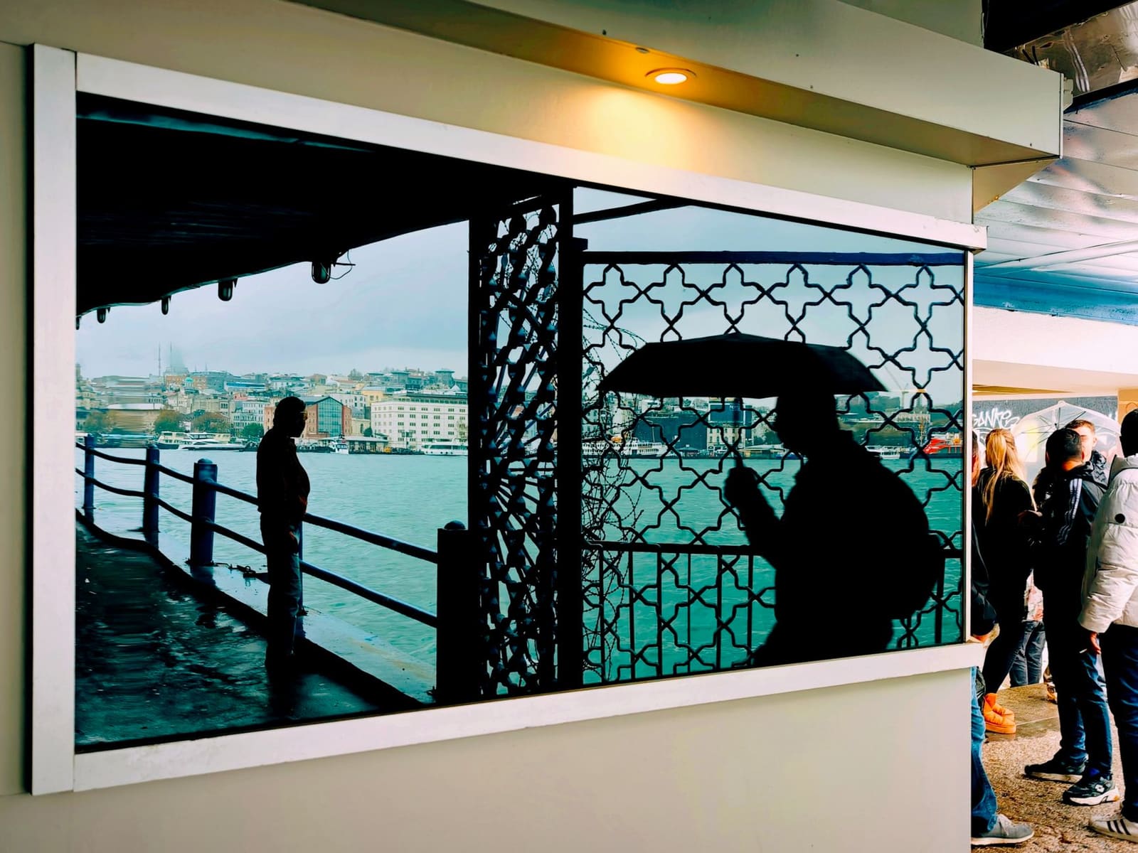 A traveler looks out through a sheltered ferry window in Istanbul.