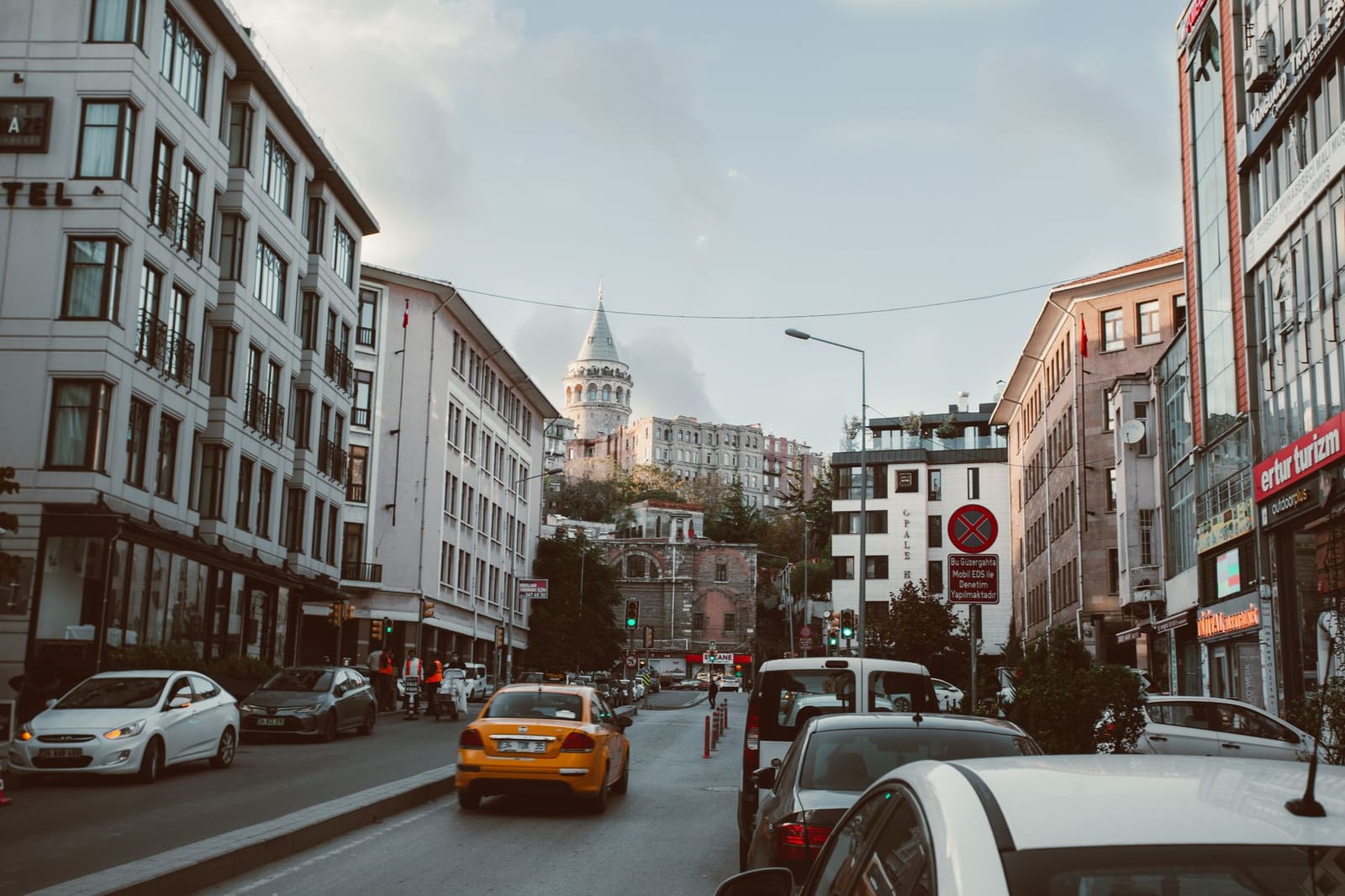 Vehicles drive past street parking signs near Galata Tower in Istanbul.