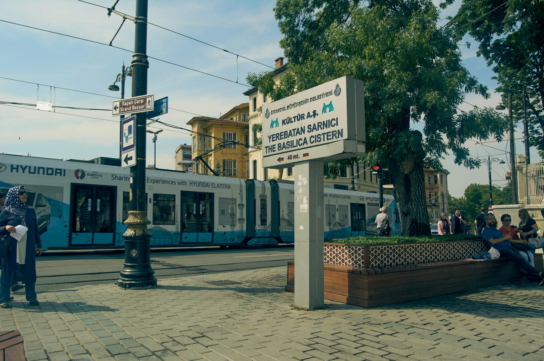 A modern T1 tram passes a directional sign for the Basilica Cistern in Istanbul.