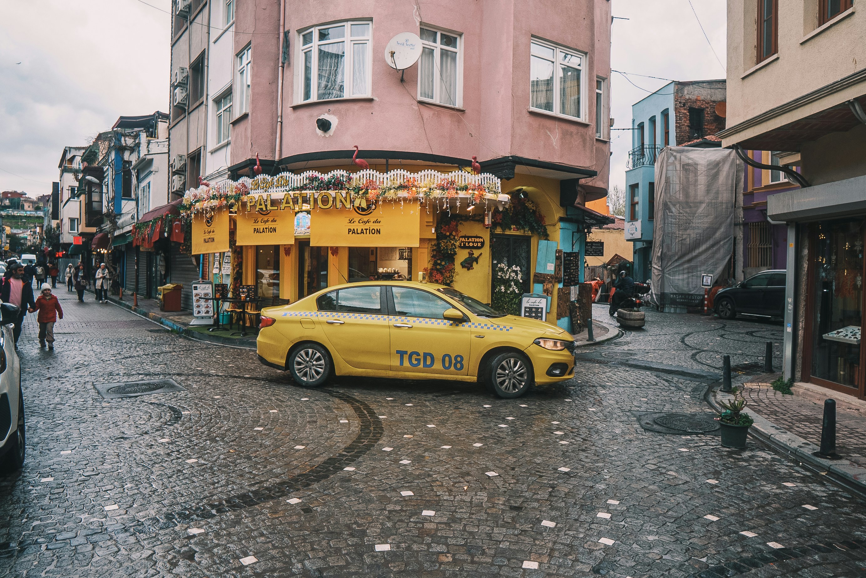 A yellow Istanbul taxi parked on a busy city street with the taksimetre sign visible.