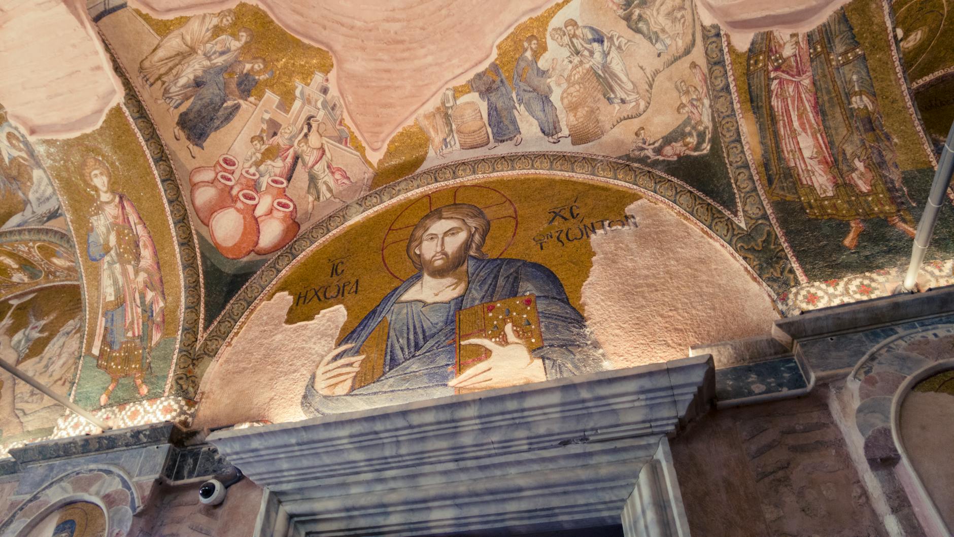 Close-up interior view of a golden mosaic depicting Christ Pantocrator holding a jeweled book above an archway inside the Kariye Mosque (Chora Church) in Istanbul.