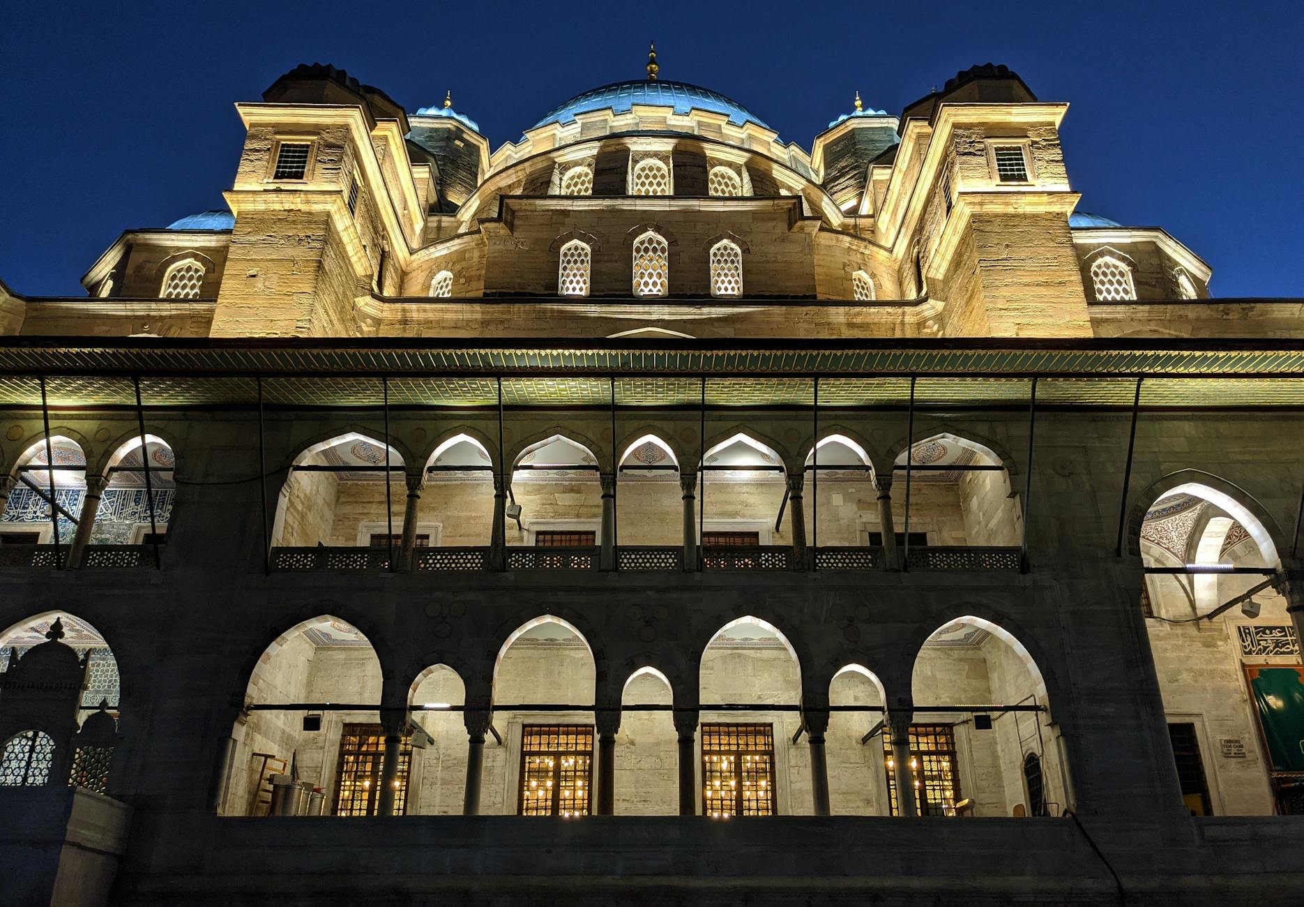 Illuminated arches and domes of the Mihrimah Sultan Mosque at night.