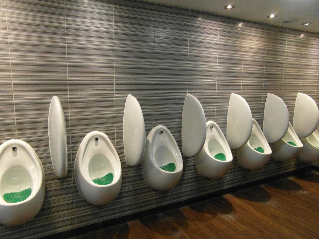 A row of contemporary egg-shaped urinals in a clean public restroom with stylish textured walls.