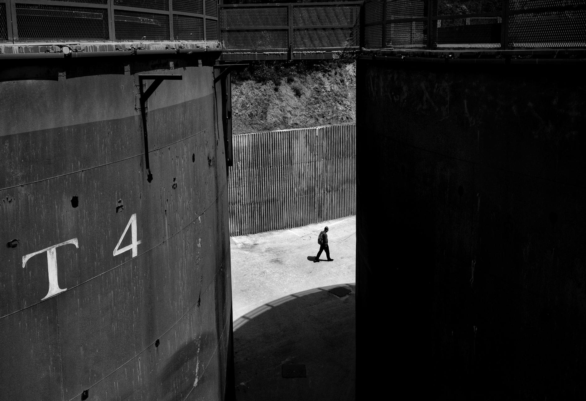 A lone silhouette walks between massive industrial storage tanks at the Müze Gazhane cultural center.