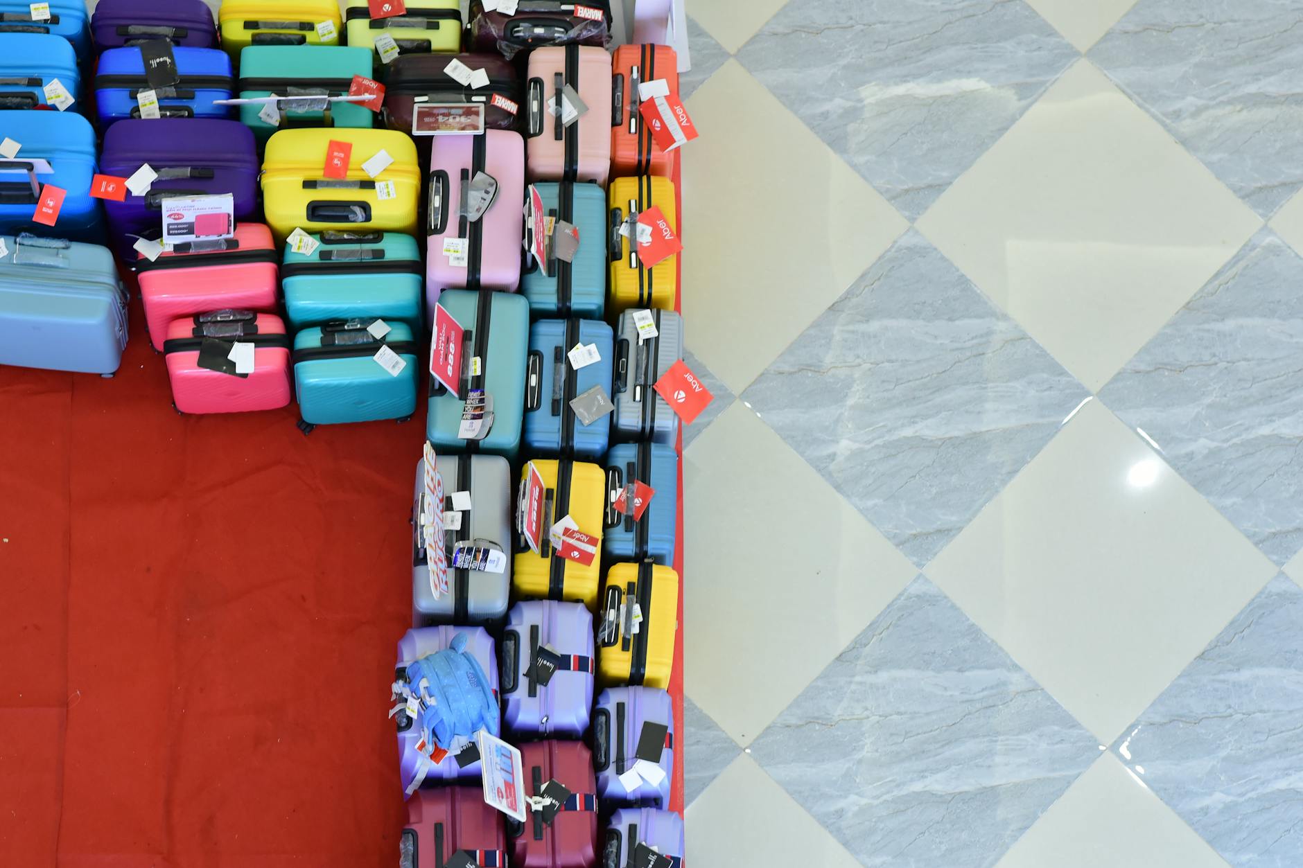 An overhead view of many colorful suitcases organized in a professional storage area.