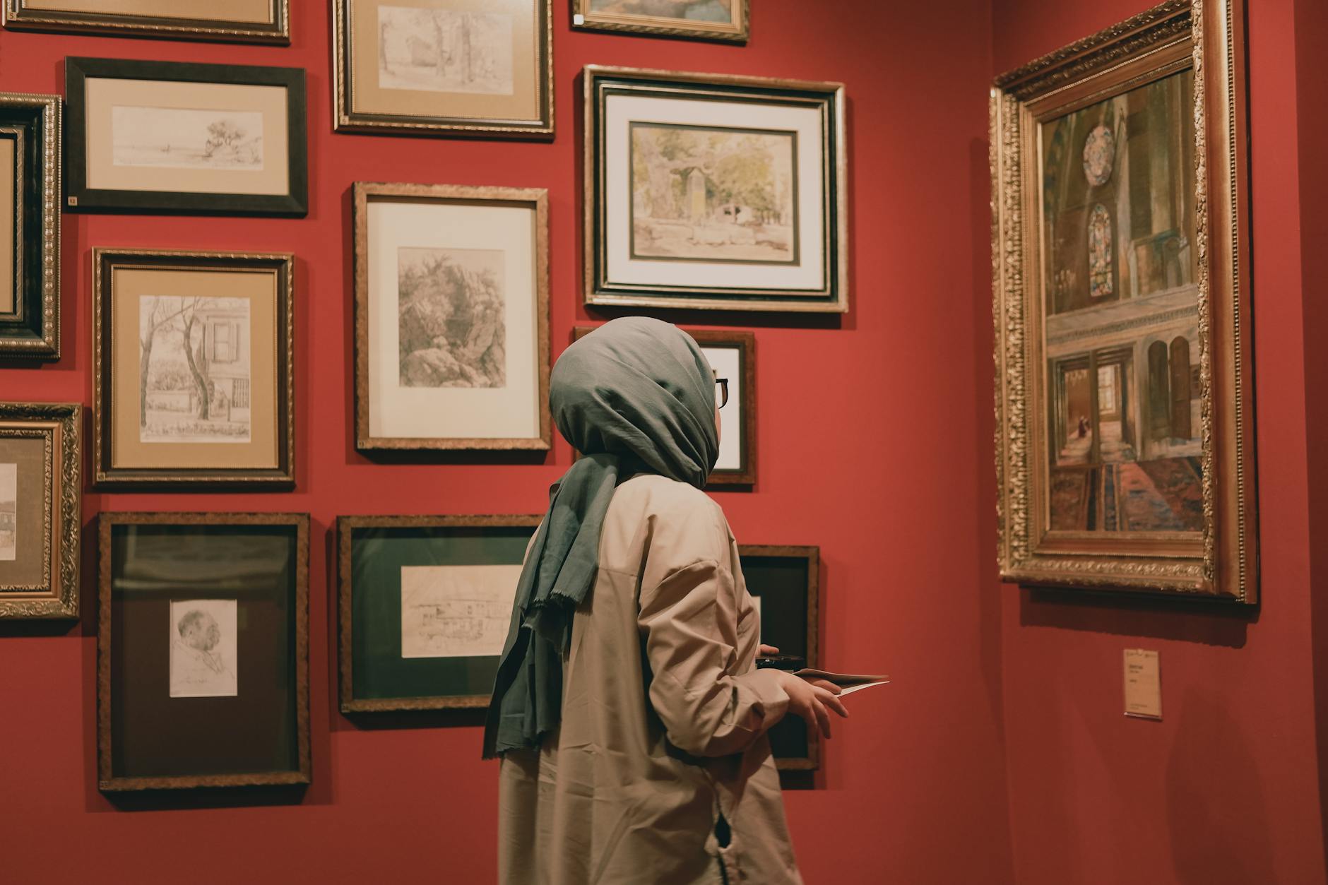 A visitor in a headscarf explores the Orientalist painting collection at Pera Museum.