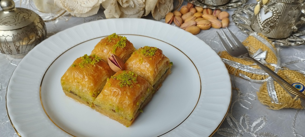 Four pieces of rich pistachio baklava served on a plate with Turkish coffee.