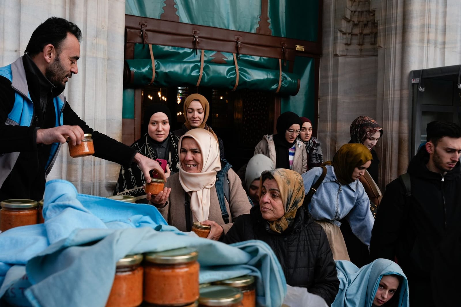 Volunteers distribute jars of food to visitors outside a historic Istanbul mosque.