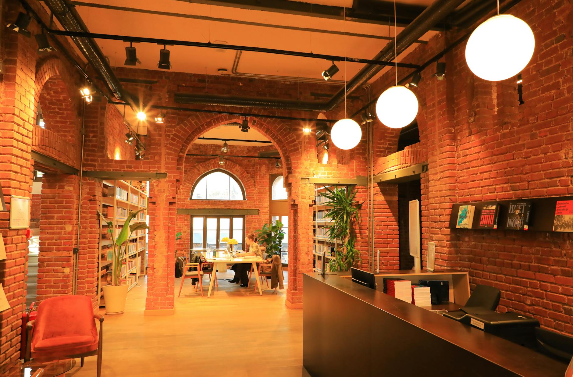 Visitors study in a historic library with exposed red brick arches and modern lighting.
