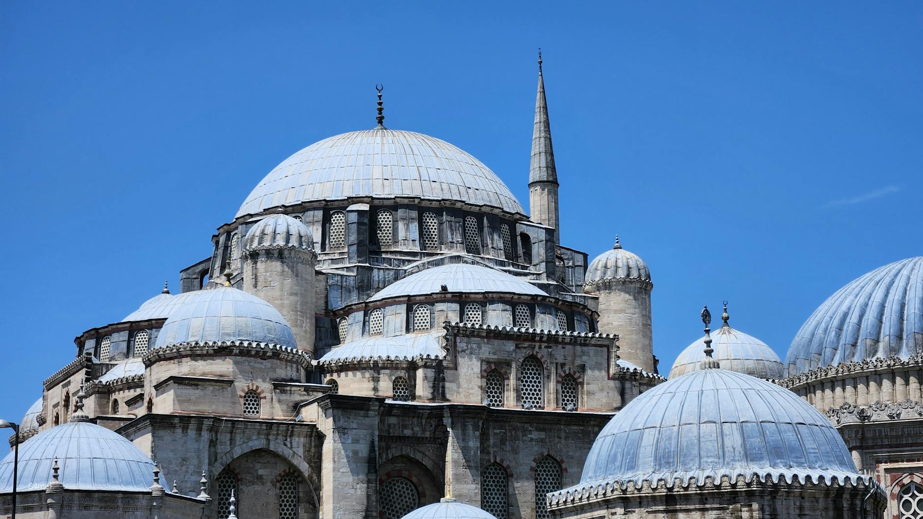Side view of the impressive stone facade and domes of Şehzade Mosque.