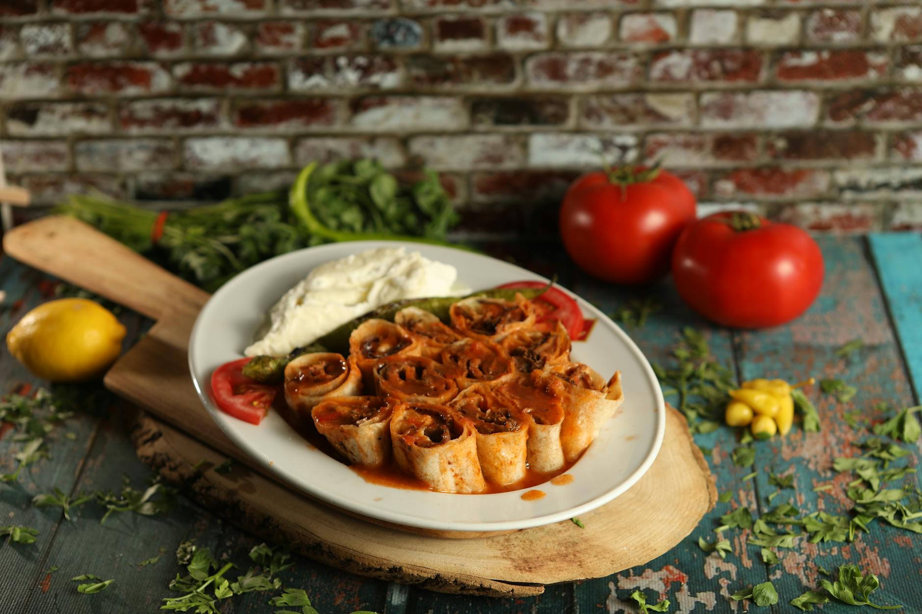 Sliced spicy Mersin style tantuni wraps served on a plate with yogurt and tomato sauce.