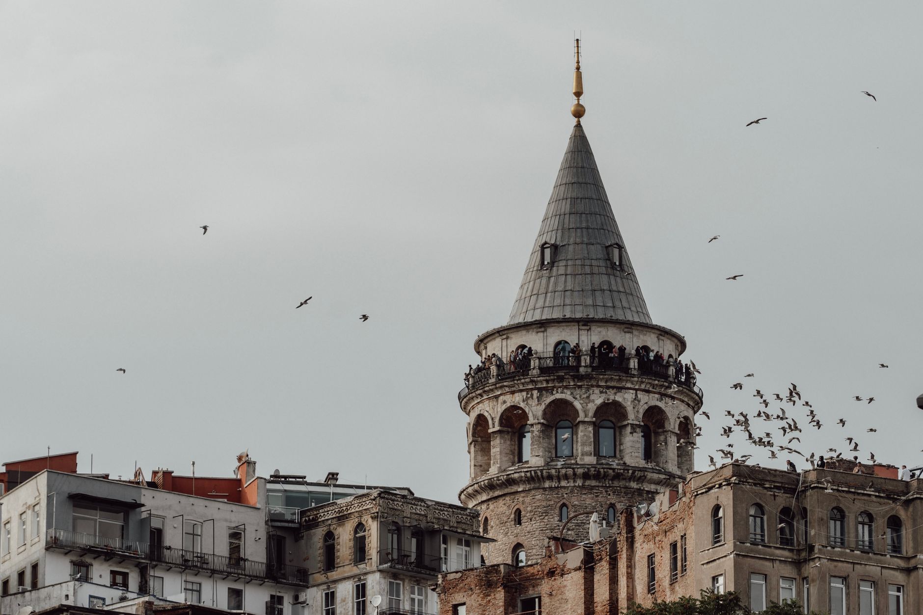Crowds of visitors stand on the open observation balcony of Galata Tower.