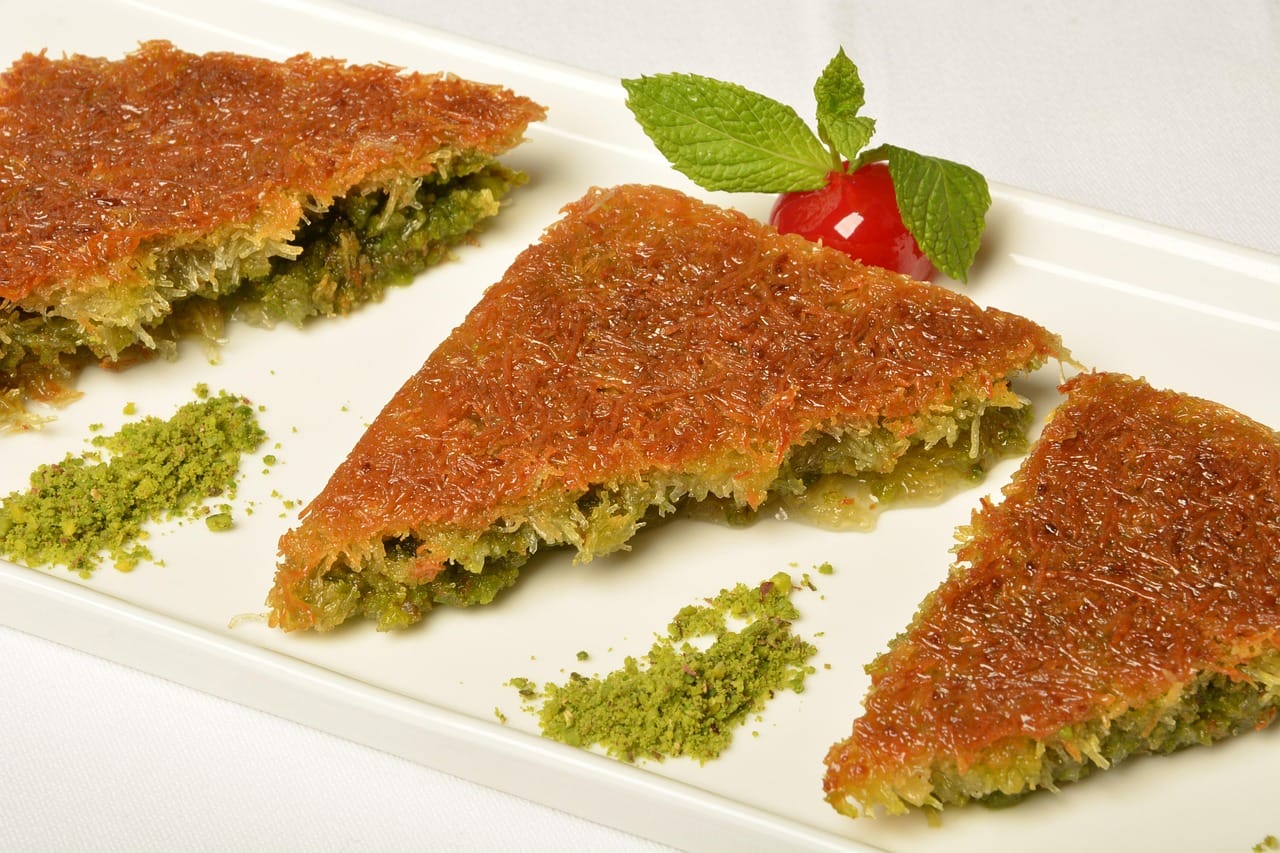 Slices of traditional sweet kunefe pastry served with ground pistachio.