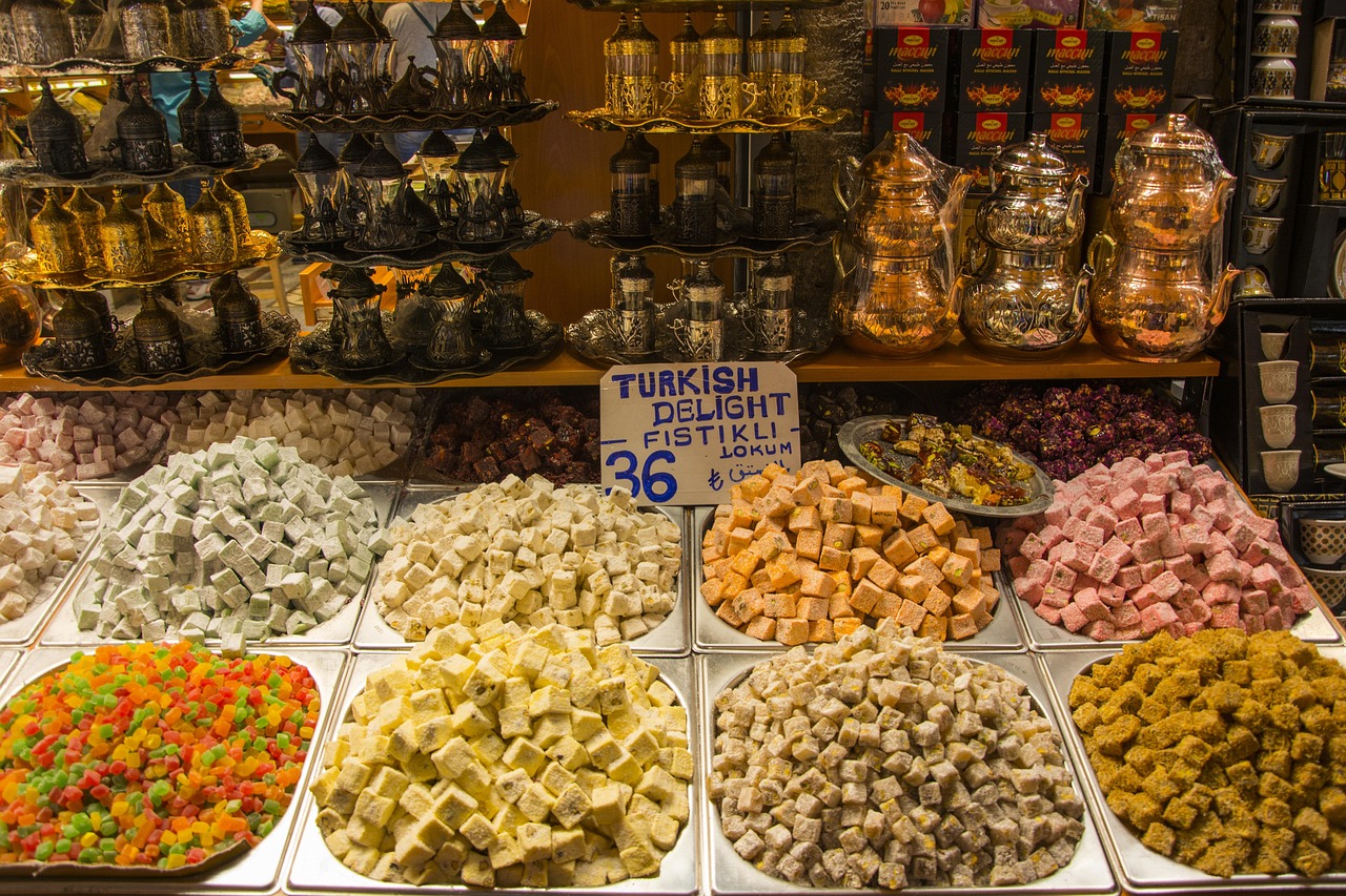 Cubed Turkish delight varieties stacked in a bazaar shop next to traditional brass teapots.
