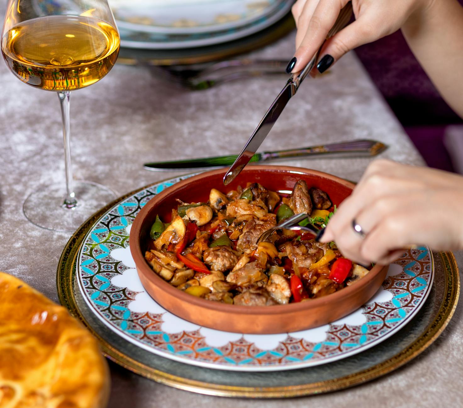 A traditional meat sauté served with a glass of amber-colored wine.