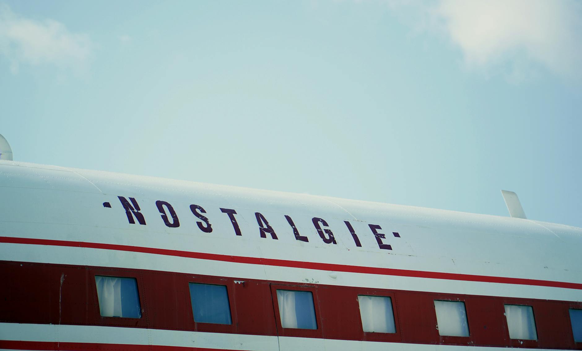 The side of a vintage white plane featuring the word Nostalgie in dark letters.